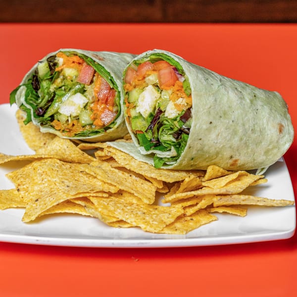 Two healthy wraps filled with fresh vegetables and chicken, served with tortilla chips.