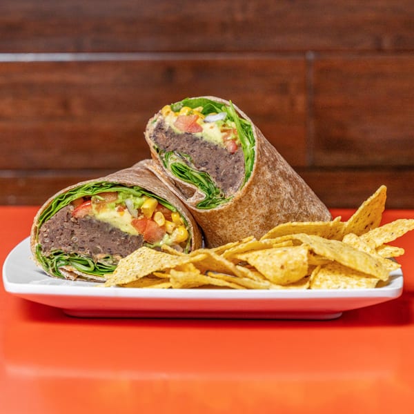 Two healthy Raw Addiction Plus wraps filled with beans, lettuce, and vegetables, served with tortilla chips.